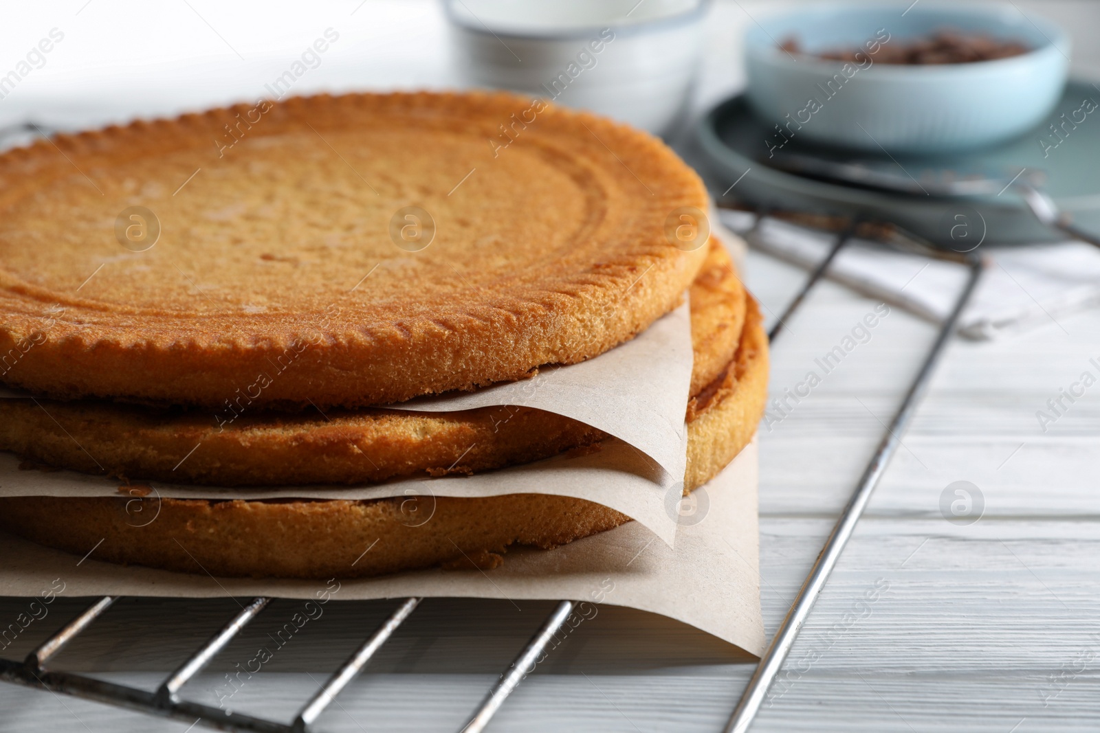 Photo of Delicious homemade sponge cakes with parchment on white wooden table, closeup