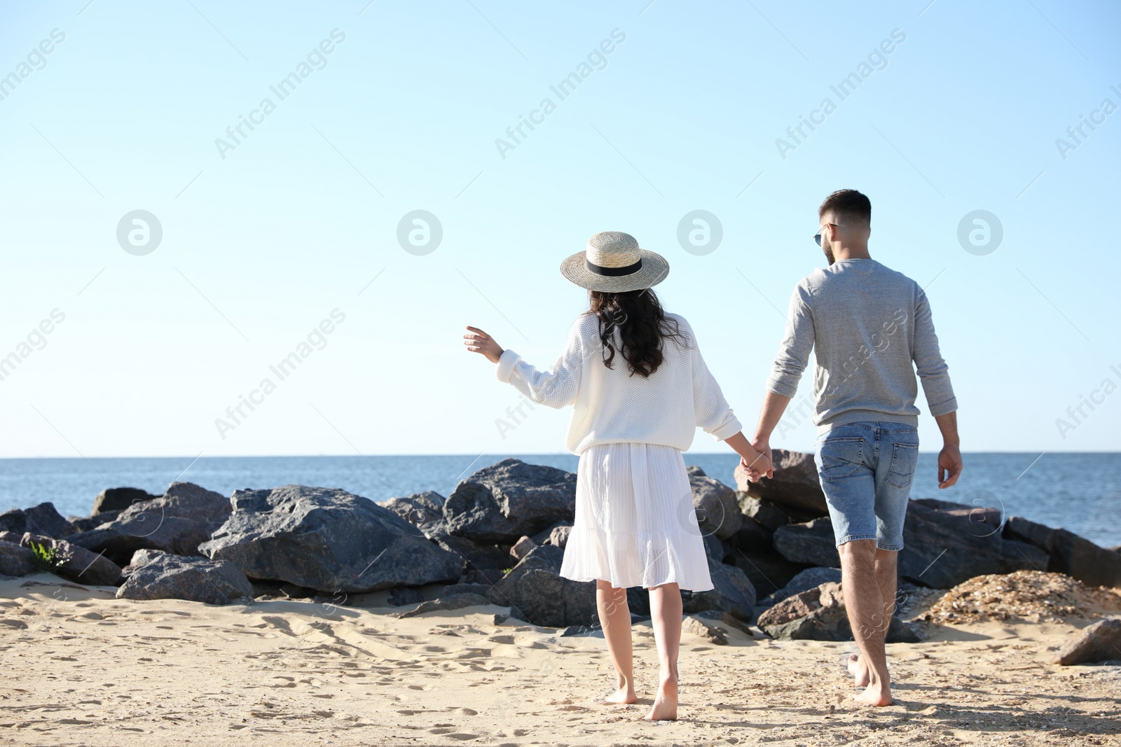 Photo of Happy young couple walking on beach near sea. Honeymoon trip