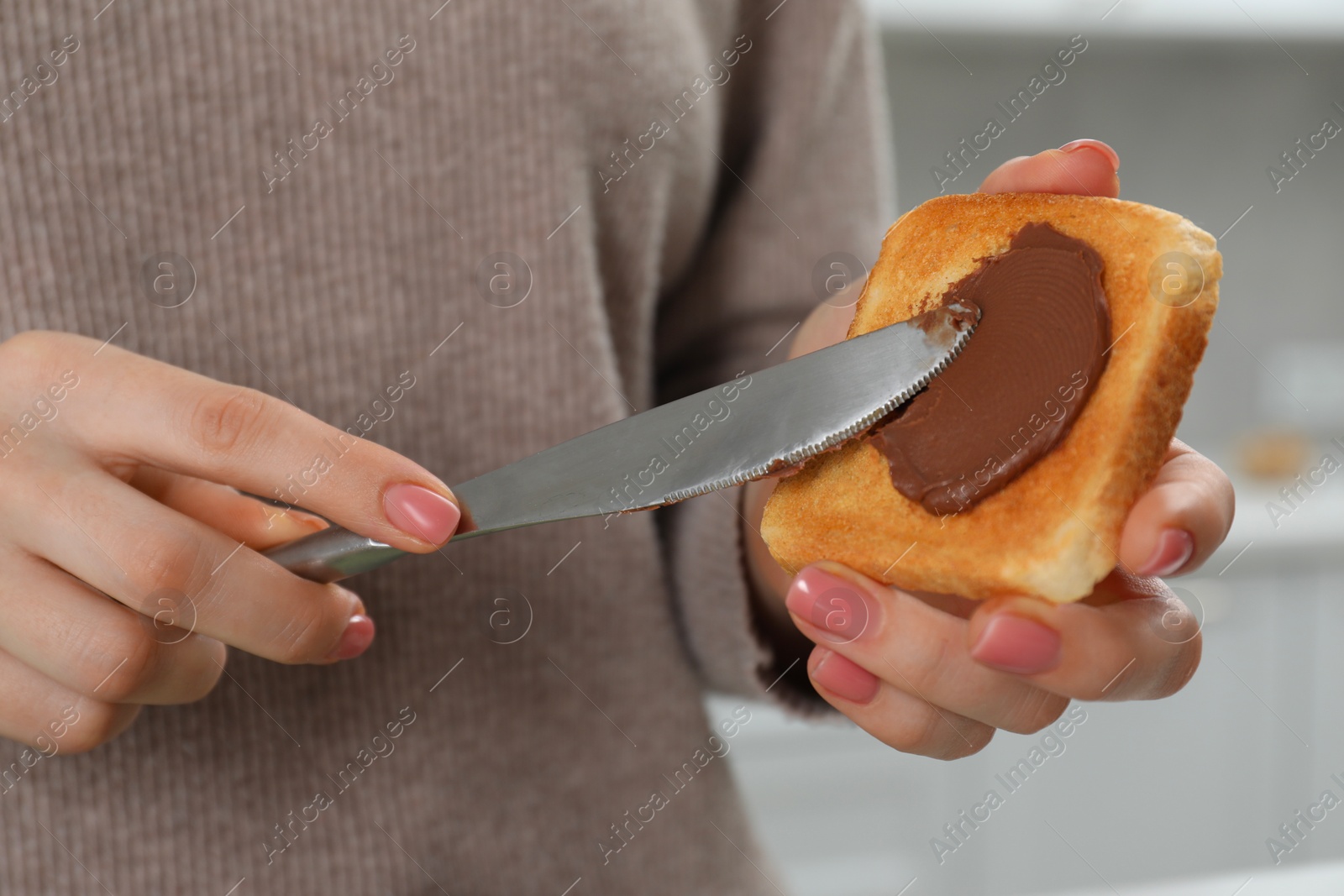 Photo of Woman spreading tasty nut butter onto toast, closeup