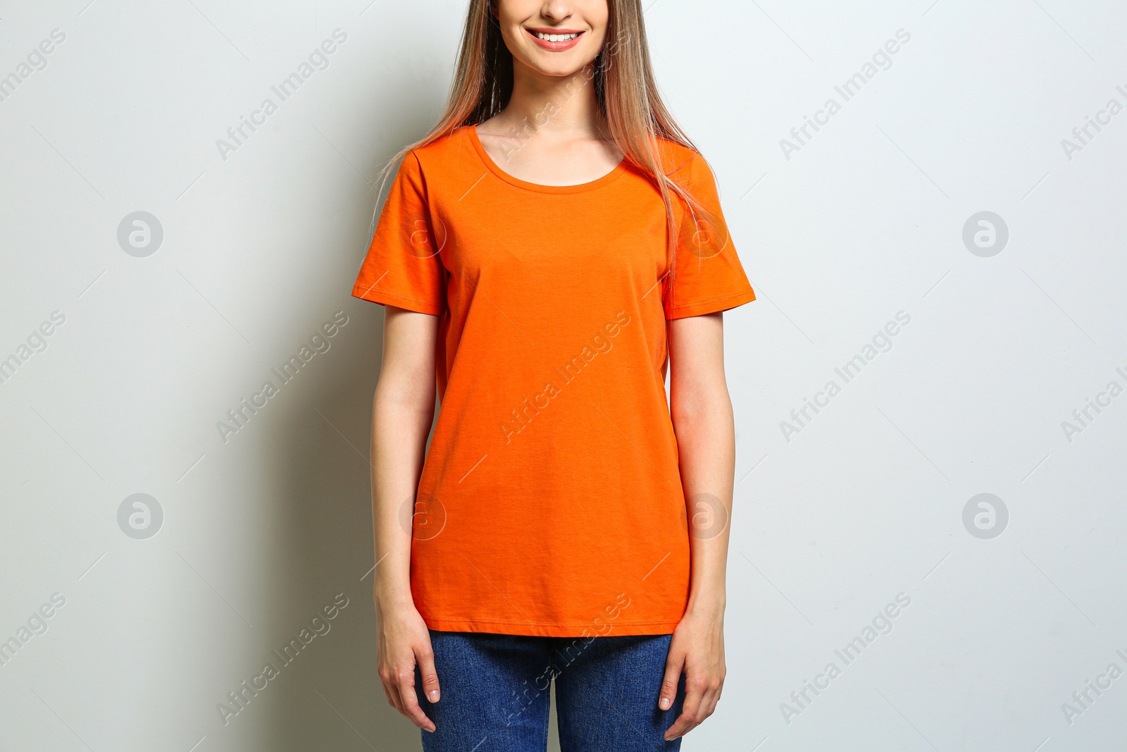 Photo of Young woman wearing blank t-shirt on light background, closeup. Mockup for design