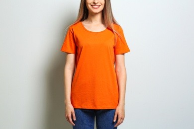 Young woman wearing blank t-shirt on light background, closeup. Mockup for design