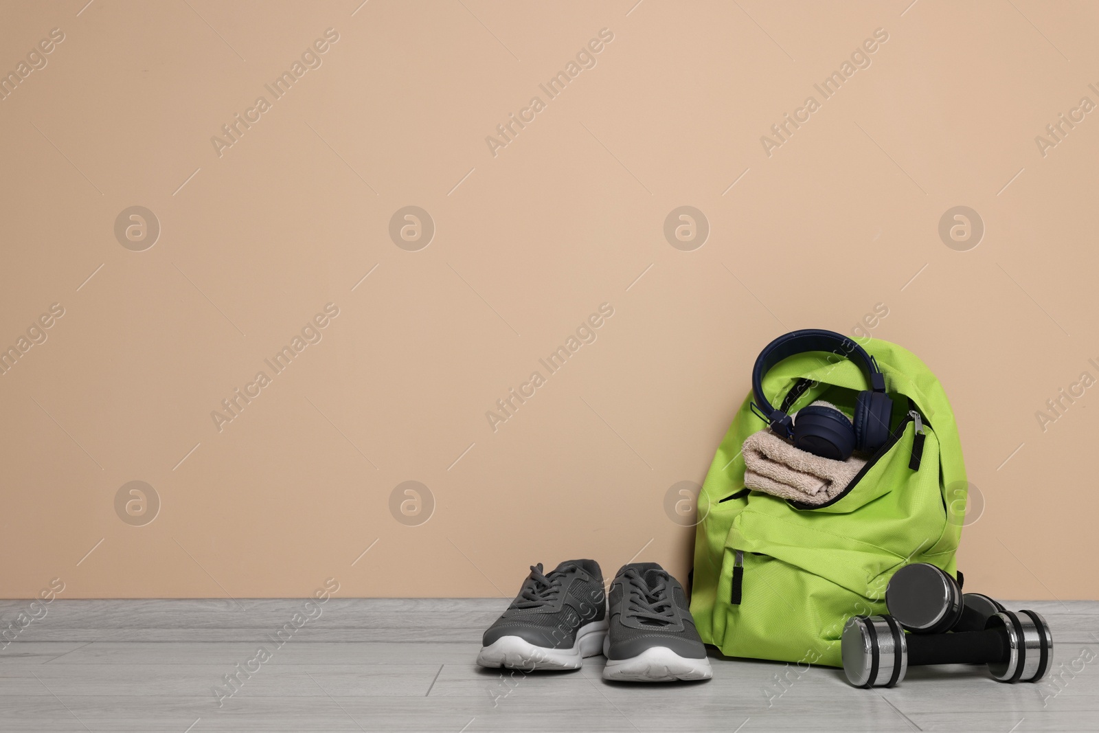 Photo of Backpack and sports equipment on floor near beige wall, space for text