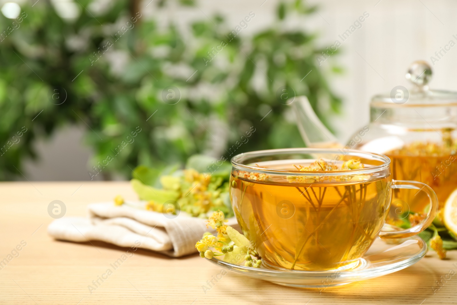 Photo of Cup of tea with linden blossom on wooden table. Space for text