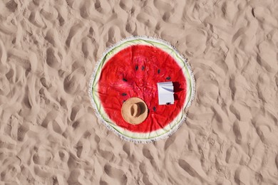 Towel with book and straw hat on sandy beach, aerial top view