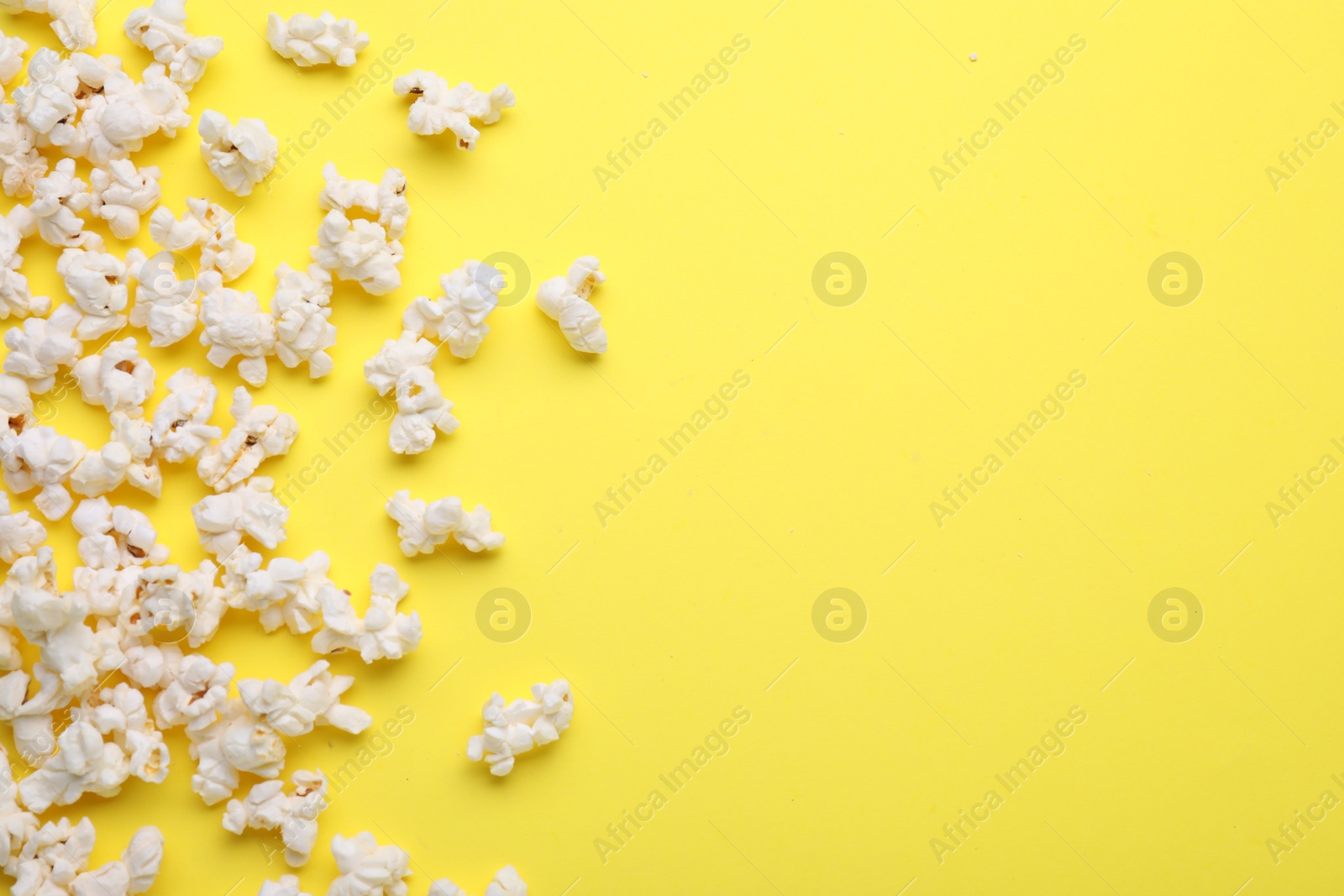 Photo of Tasty pop corn on yellow background, flat lay. Space for text