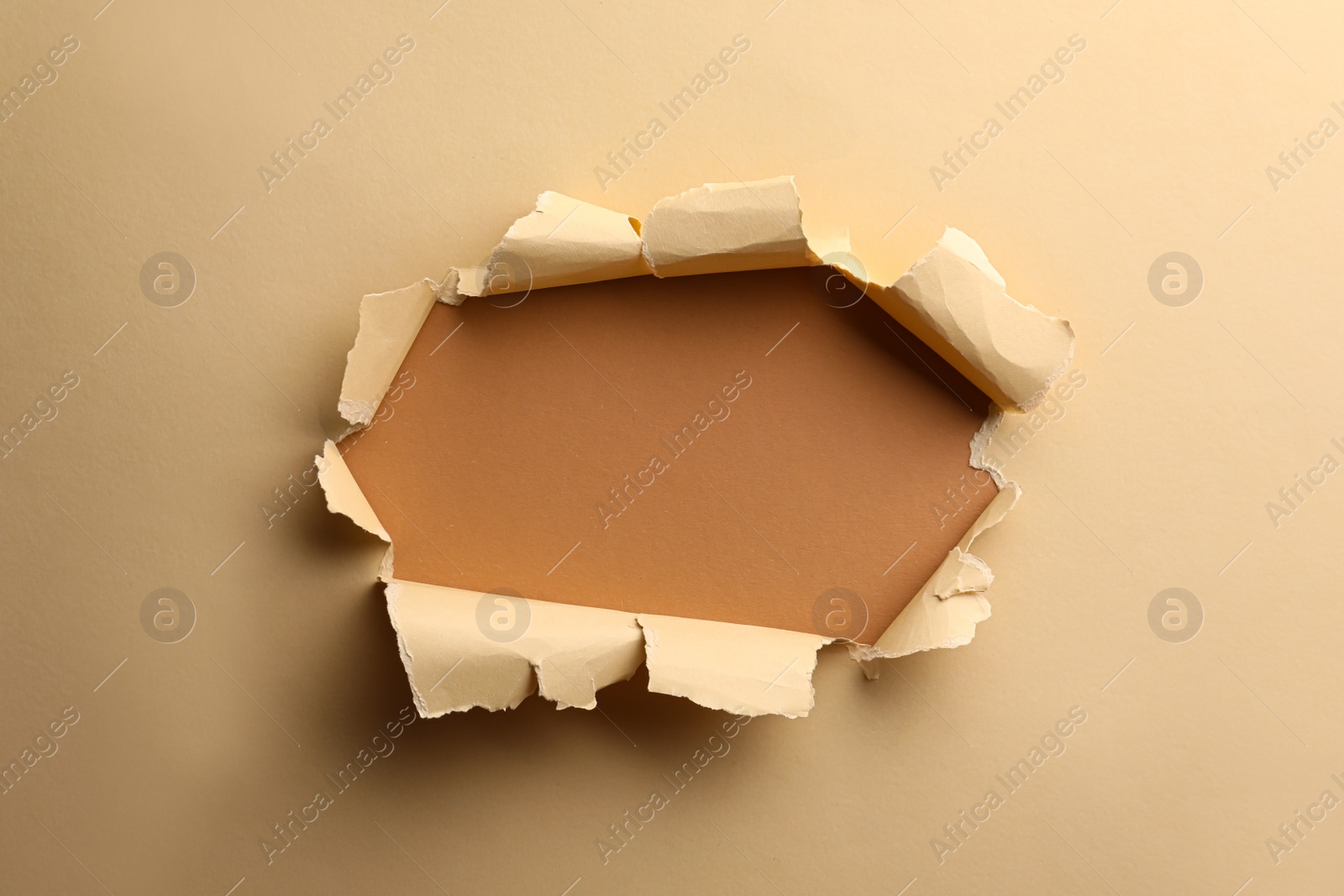 Photo of Hole in light beige paper on brown background