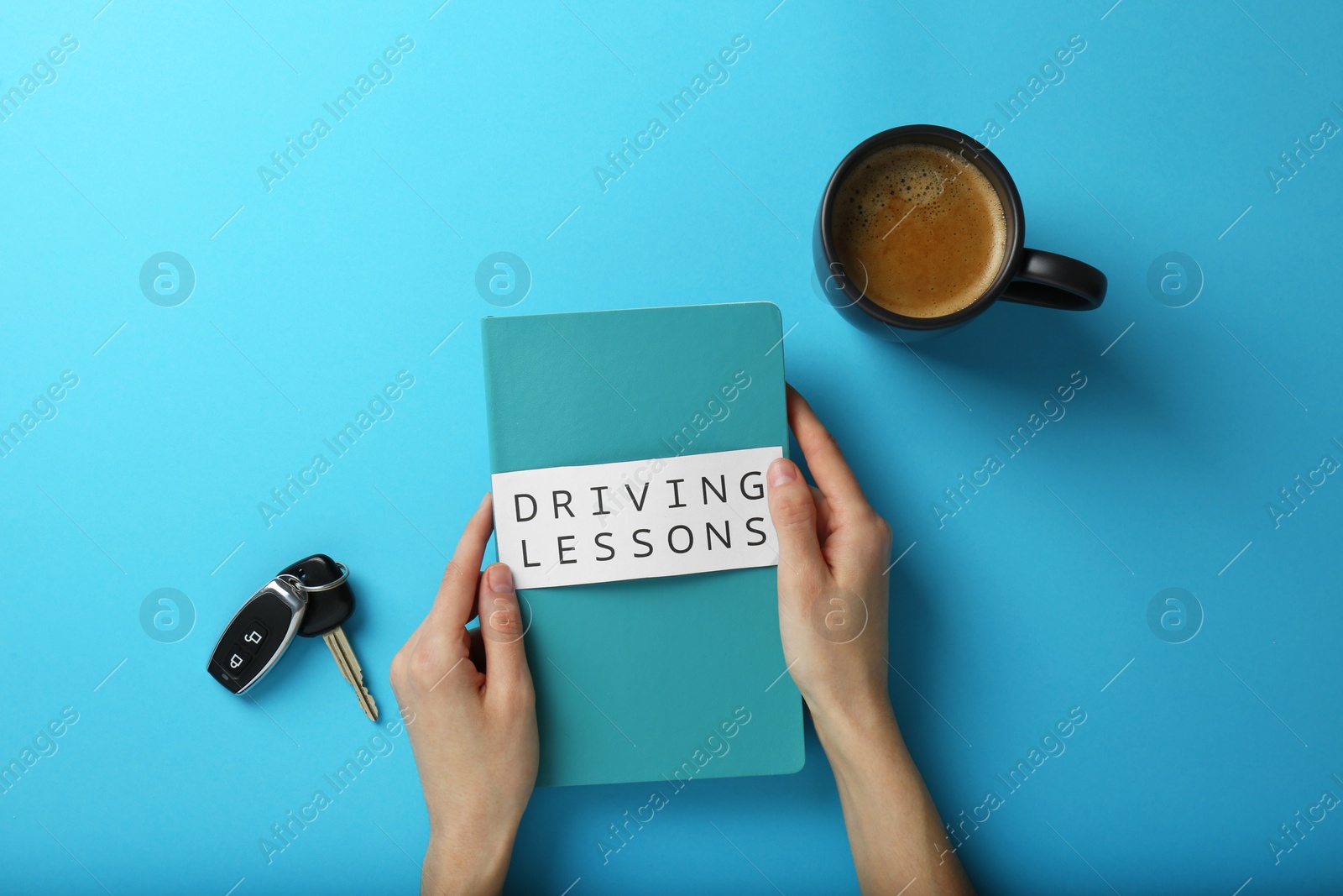 Photo of Woman with workbook for driving lessons on light blue background, top view. Passing license exam