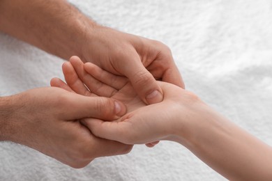 Photo of Woman receiving hand massage on soft towel, closeup