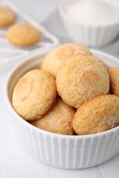 Photo of Tasty sugar cookies in bowl on white tiled table, closeup