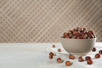 Photo of Ceramic bowl with acorns on white wooden table, space for text. Cooking utensil