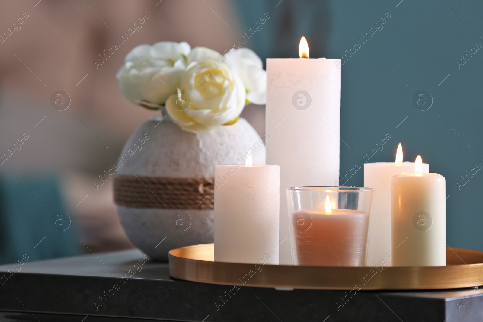 Photo of Burning candles on table against blurred background