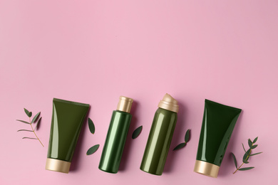 Flat lay composition with cosmetic products and leaves on pink background. Space for text