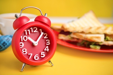 Photo of Alarm clock on yellow background, space for text. Diet regime
