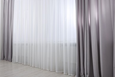 Photo of Light grey window curtains and white tulle indoors