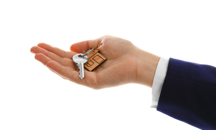 Photo of Real estate agent holding house key with trinket on white background, closeup