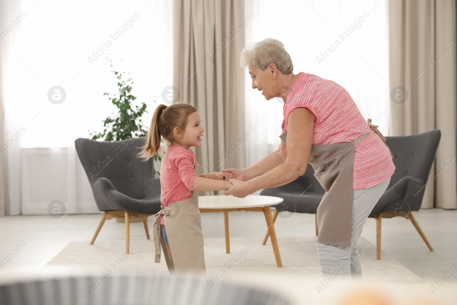 Photo of Cute girl and her grandmother dancing at home