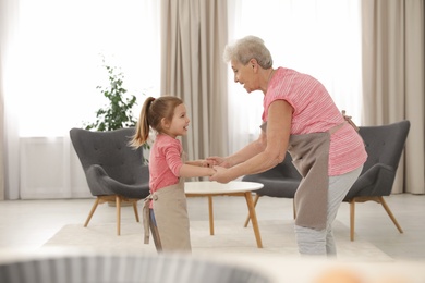 Photo of Cute girl and her grandmother dancing at home