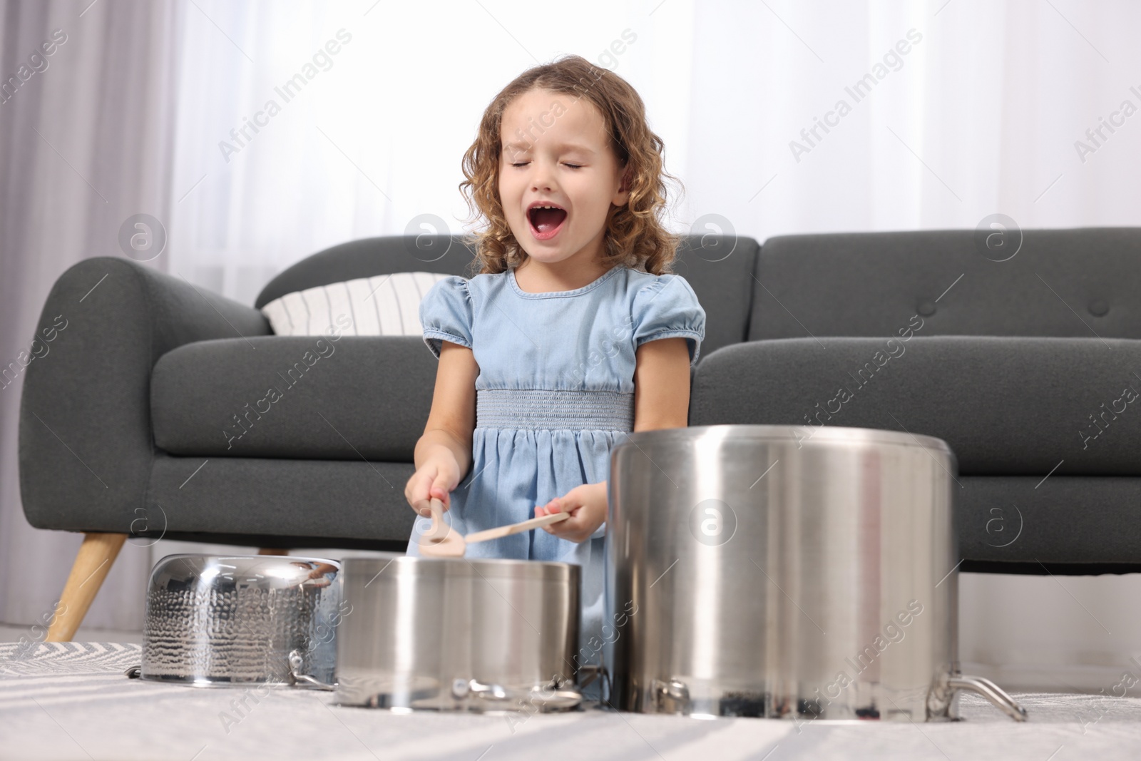 Photo of Little girl pretending to play drums on pots at home