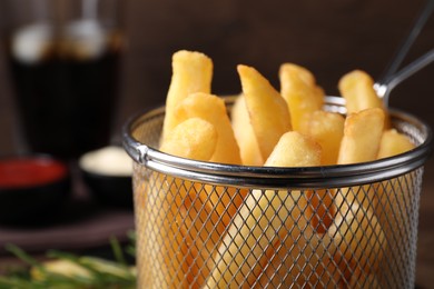 Photo of Delicious French fries in metal basket, closeup. Space for text