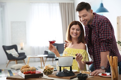 Photo of Happy couple enjoying fondue dinner at home