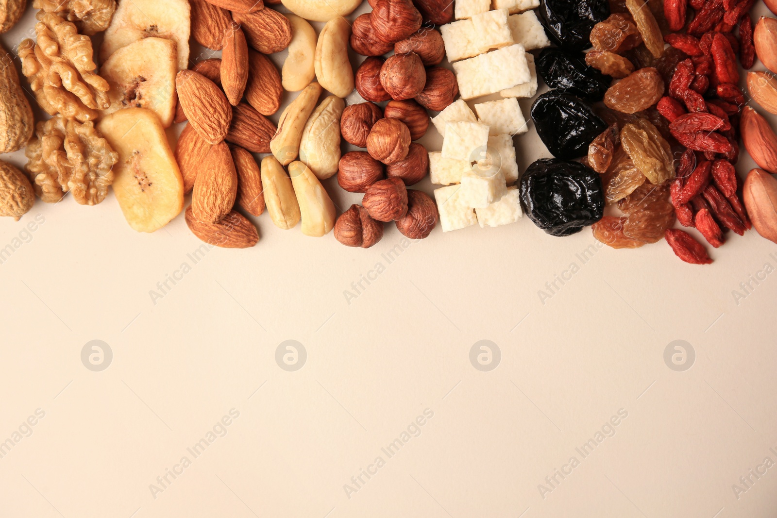 Photo of Different tasty nuts and dried fruits on beige background, flat lay. Space for text