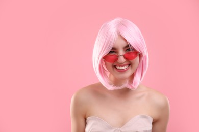 Photo of Pink look. Beautiful girl in wig and bright sunglasses on color background