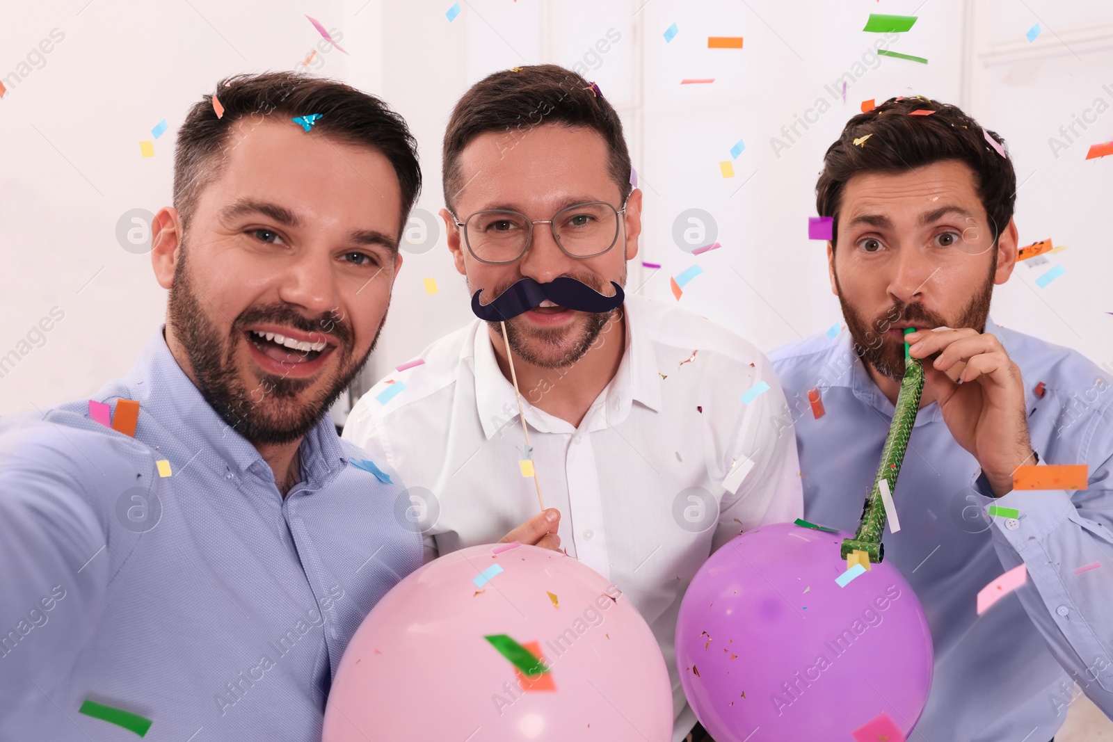 Photo of Coworkers taking selfie during office party indoors