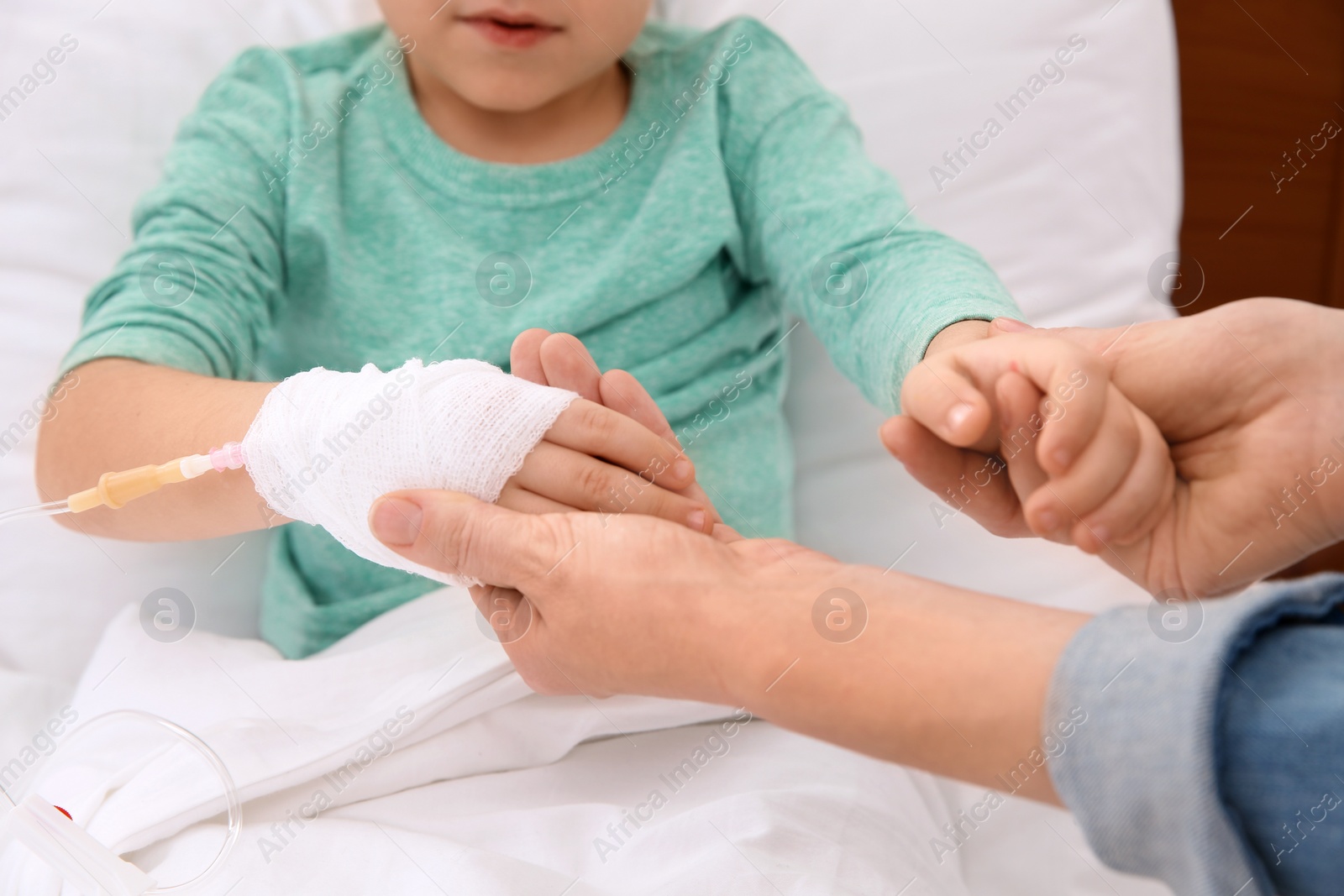 Photo of Woman visiting her little child with intravenous drip in hospital, closeup