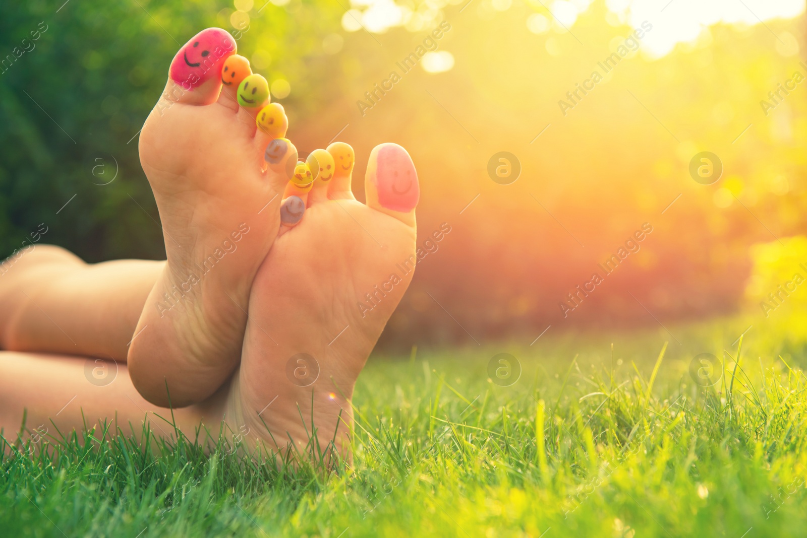 Photo of Teenage girl with smiling faces drawn on toes outdoors, closeup. Space for text