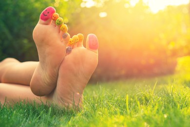 Photo of Teenage girl with smiling faces drawn on toes outdoors, closeup. Space for text