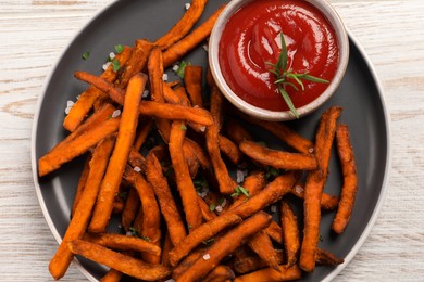 Photo of Delicious sweet potato fries served with sauce on white wooden table, top view