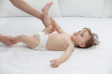 Orthopedist and cute baby on white bed