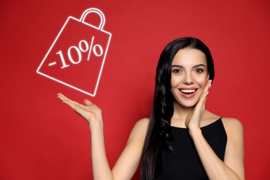 Surprised woman pointing at sign with discount on red background. Special promotion