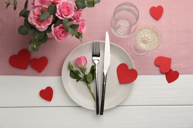 Photo of Romantic place setting with flowers and red paper hearts on white wooden table, flat lay. St. Valentine's day dinner