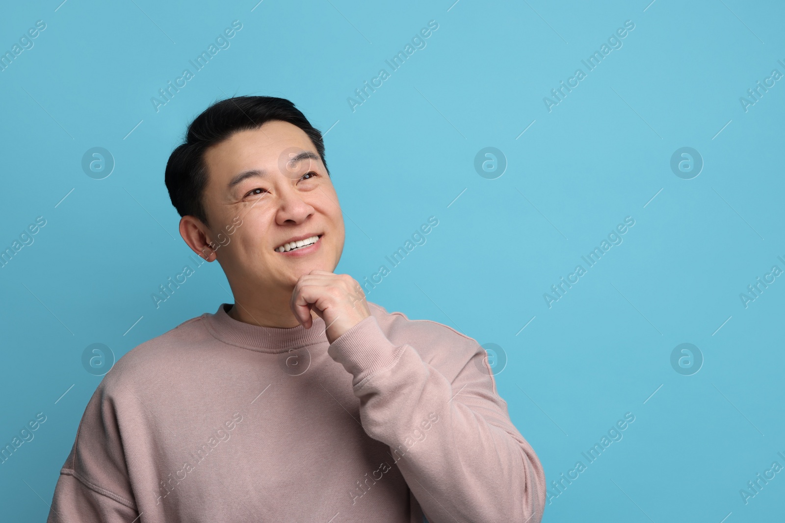 Photo of Portrait of happy man on light blue background. Space for text