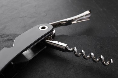 Photo of One corkscrew (sommelier knife) on grey textured table, closeup