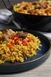 Photo of Delicious pilaf with meat, carrot and chili pepper on wooden table, closeup