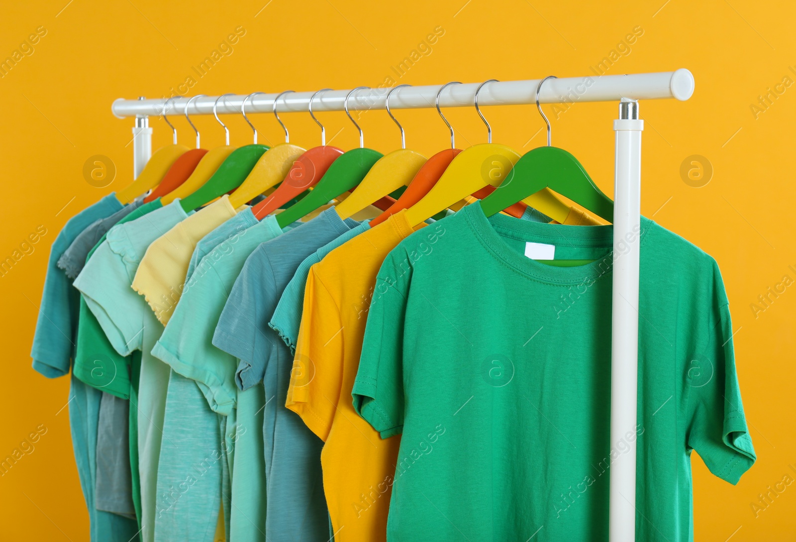 Photo of Rack with stylish children clothes on yellow background