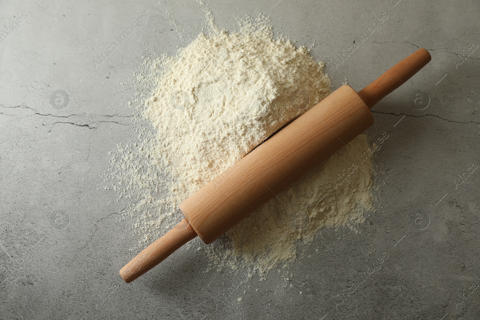 Photo of Flour and rolling pin on grey table, top view