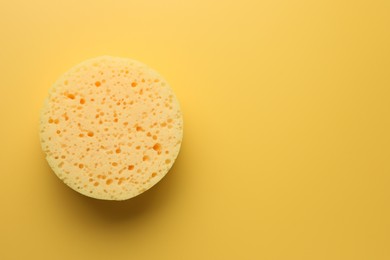 Photo of Sponge on yellow background, top view. Space for text