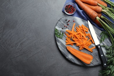 Flat lay composition with raw carrots on grey table. Space for text