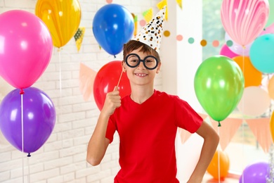 Photo of Happy boy near bright balloons at birthday party indoors