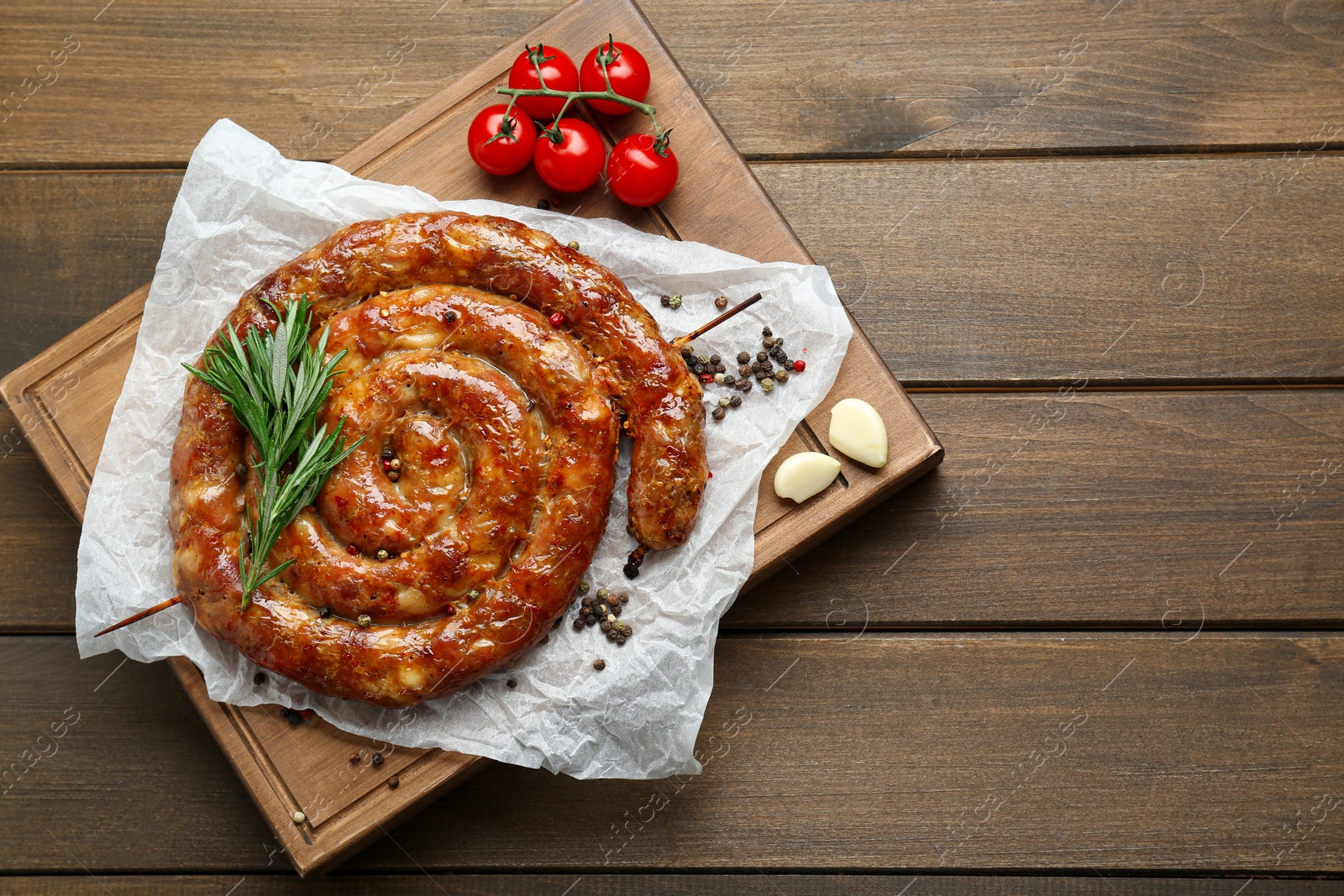 Photo of Delicious homemade sausage with spices and tomatoes on wooden table, top view. Space for text