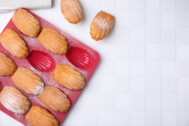 Photo of Delicious madeleine cookies and baking mold on white table, flat lay. Space for text