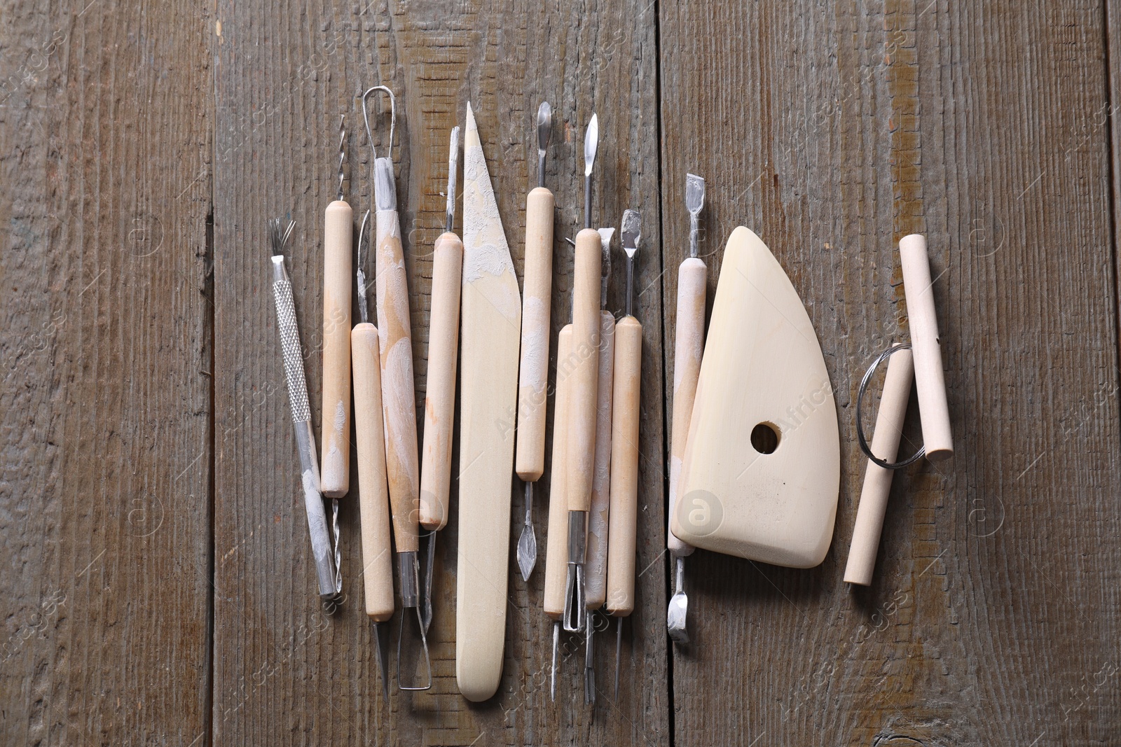 Photo of Set of different clay crafting tools on wooden table, top view