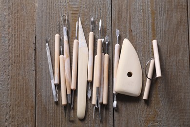 Set of different clay crafting tools on wooden table, top view