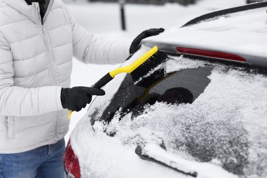 Man cleaning snow from car window outdoors, closeup