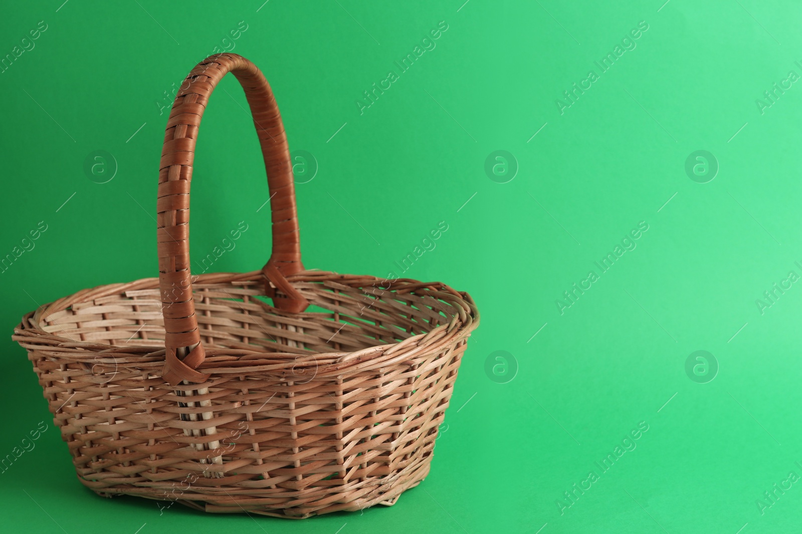 Photo of Empty wicker basket on green background, space for text. Easter item