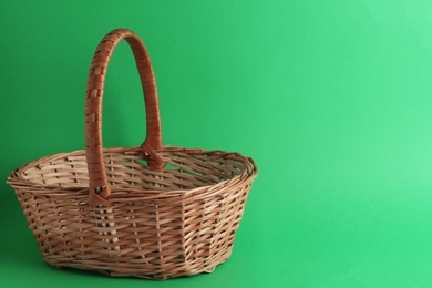 Photo of Empty wicker basket on green background, space for text. Easter item