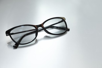 Photo of Stylish black eye glasses on white table. Space for text